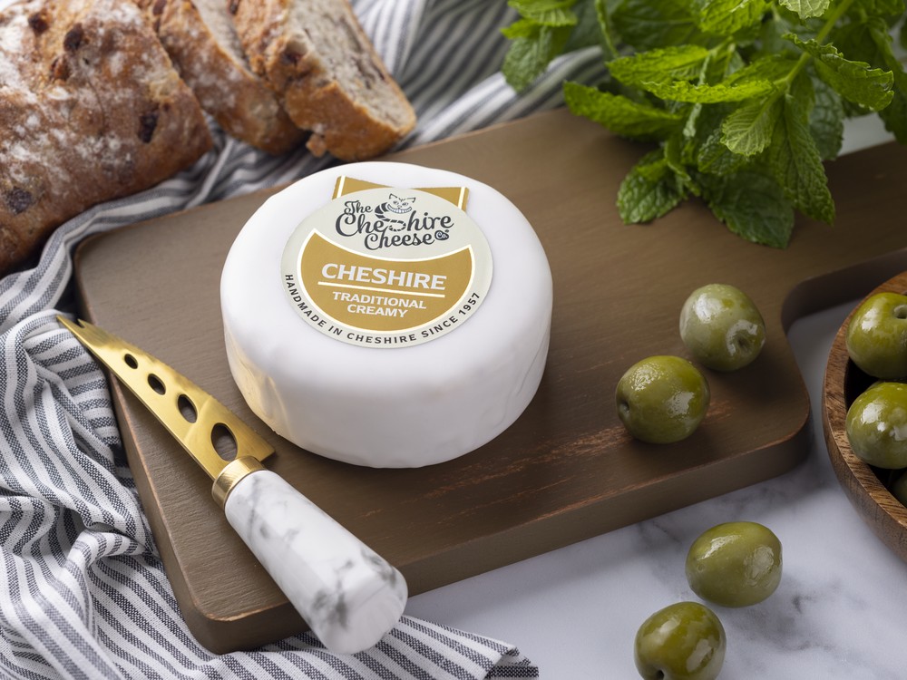 Creamy Cheshire on a wooden board with olives and herbs