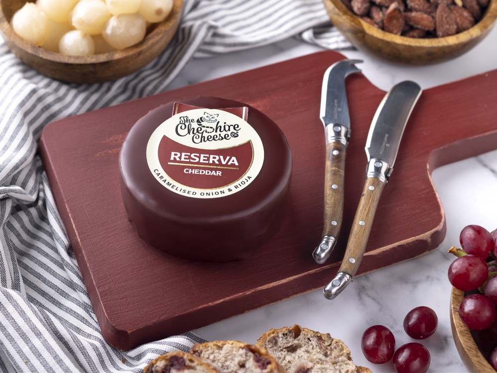 Reserva Caramelised Onion & Rioja Red Wine Cheddar on a wooden board with berries and bread slices