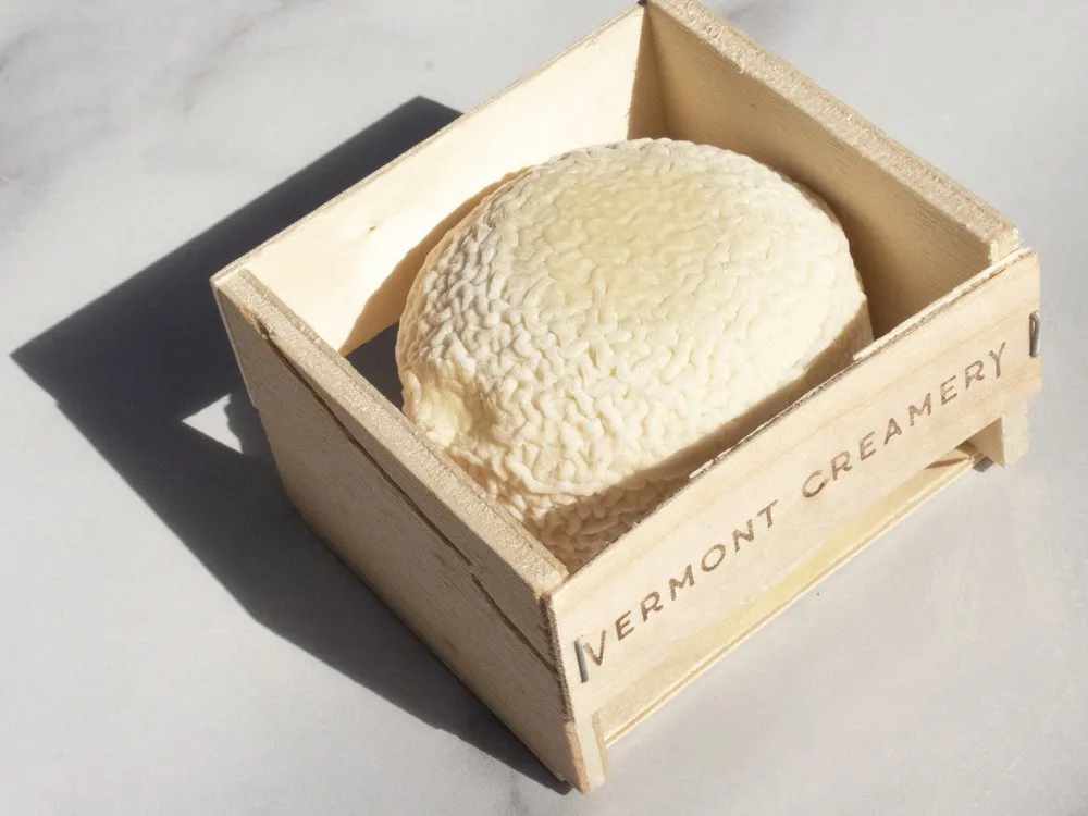 A Coupole cheese with a wrinkled rind nestled in a wooden box from Vermont Creamery