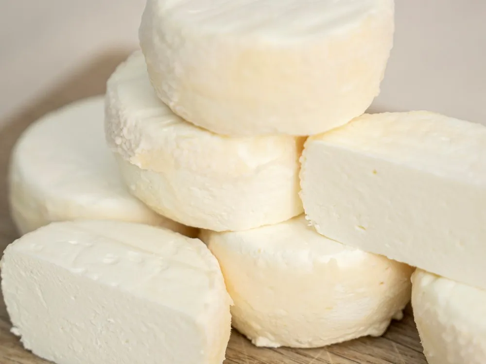 Discs of Castillon Frais Cheese stacked neatly on a wooden surface