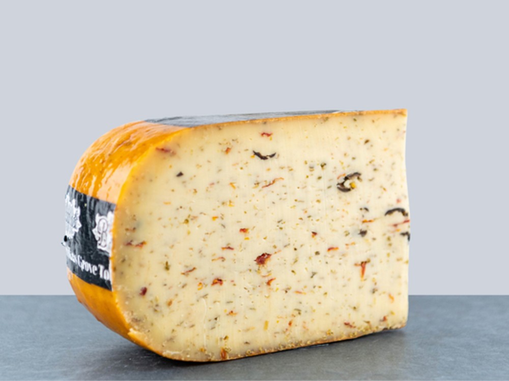 A slice of Olive and Tomato Farmhouse cheese, a Dutch artisan cheese with fresh olives and tomatoes