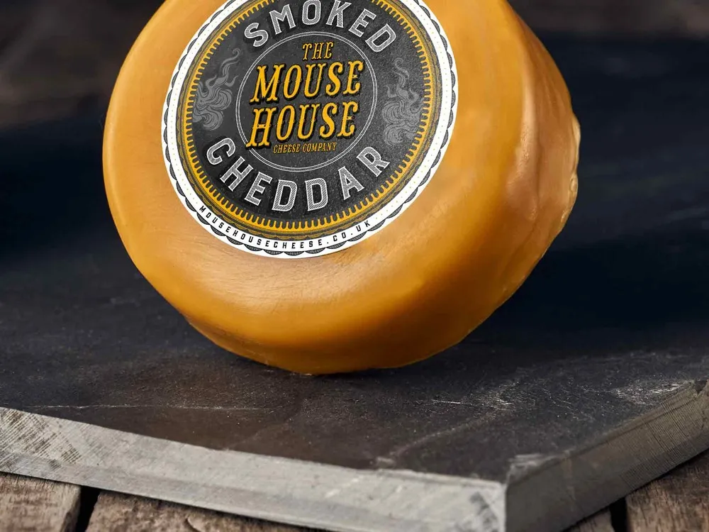 A wax-coated Mouse House Smoked Cheddar is placed on a wooden surface