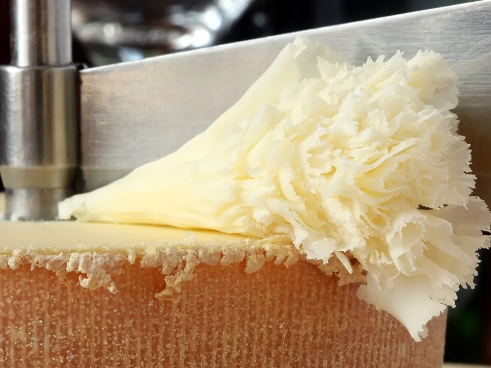 A wheel of Tête de Moine cheese with rosettes (cheese curls) alongside a Cheese Curler