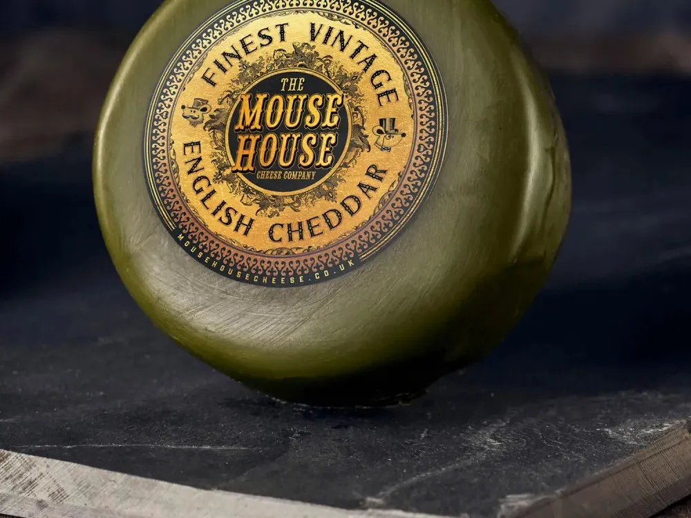 A wax-coated disc of Finest Vintage Cheddar cheese is placed on a black marble