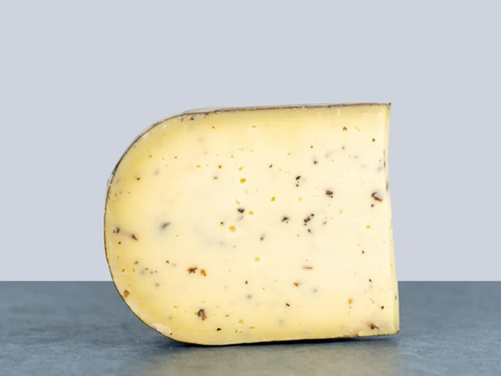 A slice of Truffle Gouda Cheese - Dutch Goat's Milk Cheese with Black Summer Truffles