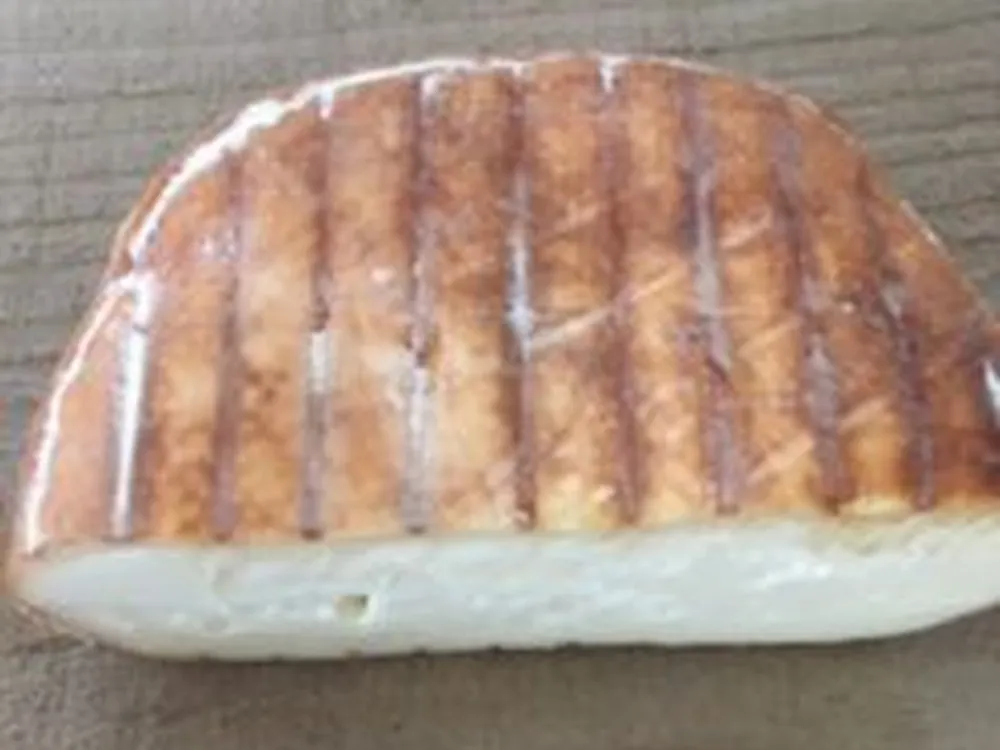 A slice of Brun de Noix cheese on a wooden surface