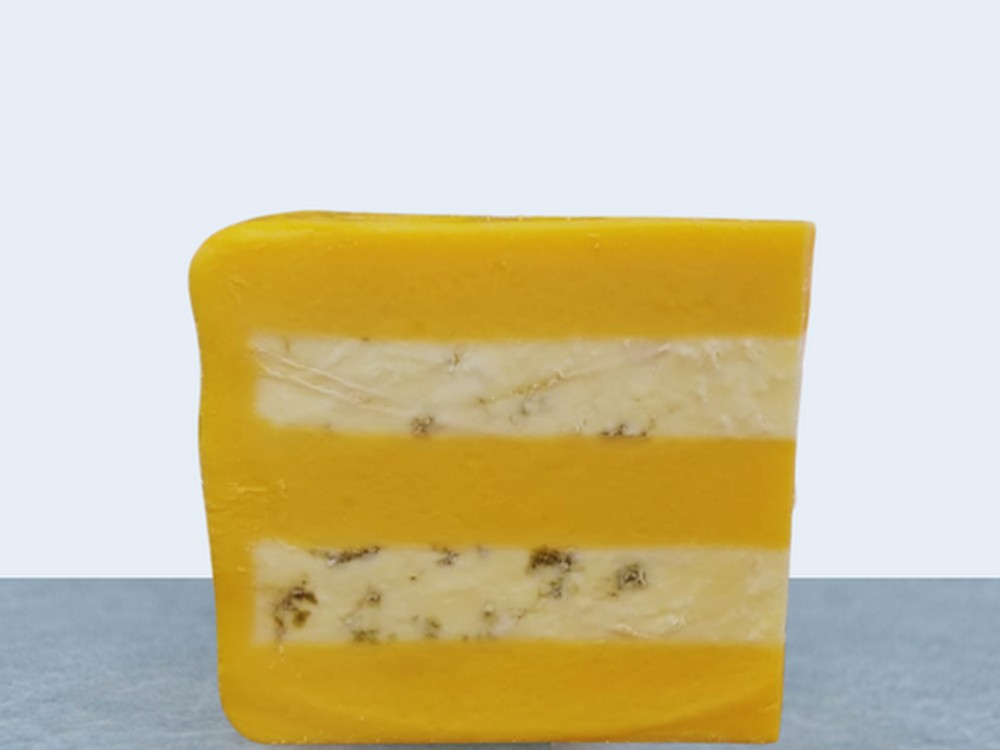 A wedge of Huntsman Cheese, displaying layers of Double Gloucester and Blue Stilton