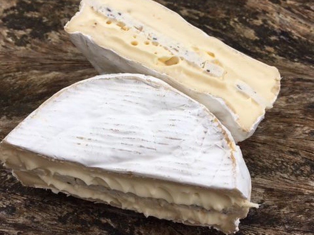 Oxford College White with Truffles, a rich Brie-style cheese layered with black truffle arranged on a wooden surface