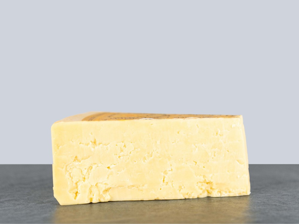 Wookey Hole Farmhouse Cheddar - a slice of a cheese with smooth, crumbly texture