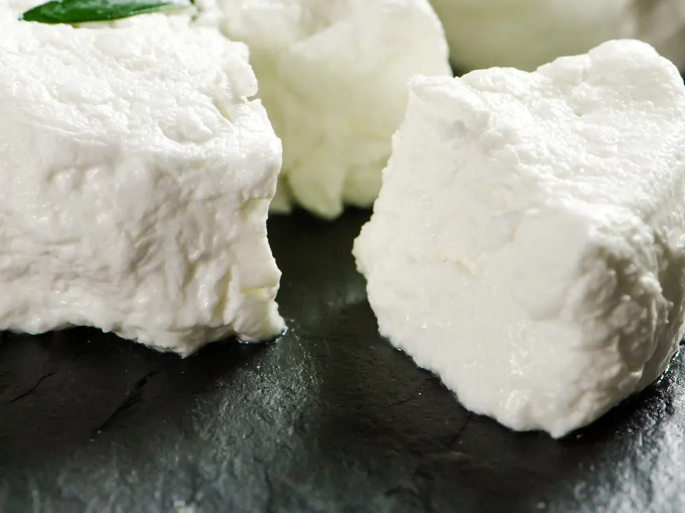 The City Goat cheese chunks garnished with basil leaf on a black marble