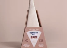 A packet of Bree vegan cheese, wrapped in a white sheet, is set against a beige background.