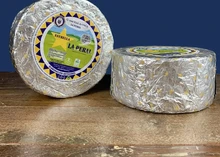 Discs of La Peral cheese, wrapped in silver paper with labels, are arranged on a wooden surface