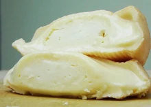 Munster cheese, revealing its soft interior and washed rind, resting on a wooden surface