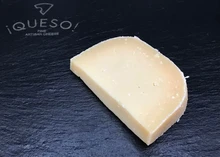 A slice of Old Winchester cheese, showcasing its pale creamy interior, rests on a black marble