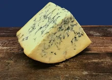 A wedge of Stichelton cheese showcasing its ivory interior streaked with blue veins