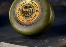 A wax-coated disc of Finest Vintage Cheddar cheese is placed on a black marble