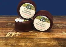 Small discs of Wensleydale and Cranberry cheese stacked on a wooden surface