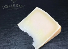 A slice of Zamorano cheese showing pale yellow interior placed on a black marble