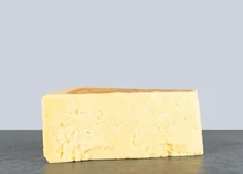 A wedge of Wookey Hole Farmhouse Cheddar showcasing its golden hue and crumbly interior