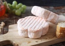 Floral-shaped Saint Albray cheeses are stacked on a cutting board, accompanied by slices of bread