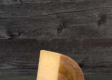 A wedge of Manchego Gran Reserva Cheese on a wooden surface