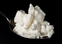 Quark on a spoon, showcasing its soft and creamy texture against a black background