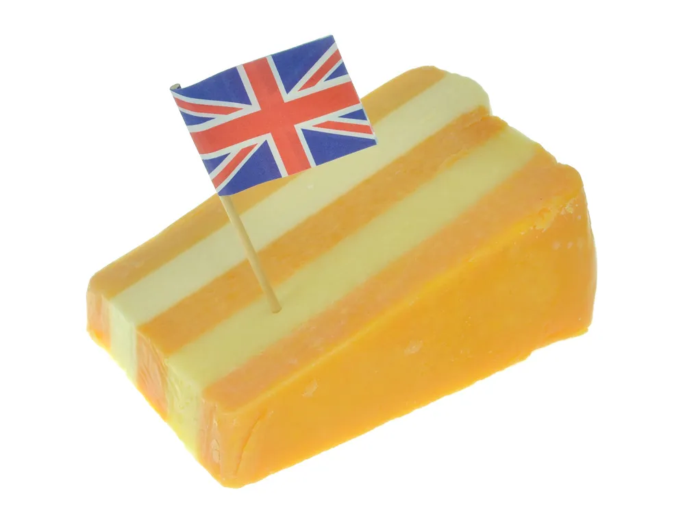 A wedge of Five Counties cheese with UK flag set against white background