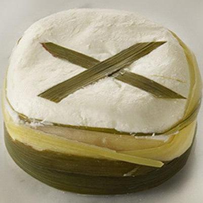 Grassias cheese wrapped in lemongrass showcasing its soft, clay-like texture