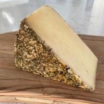 A slice of Heublumenkäse, with its vibrant hayflower-coated rind and creamy interior, sits elegantly on a wooden surface.