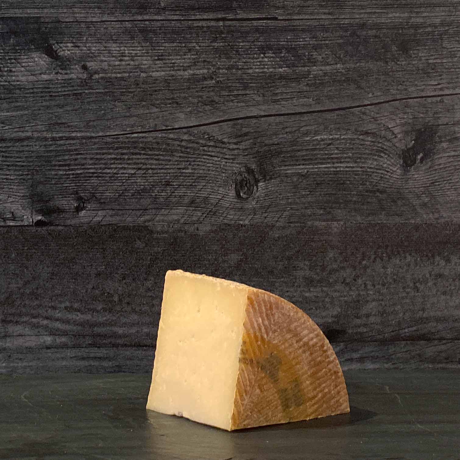 A wedge of Manchego Gran Reserva Cheese on a wooden surface