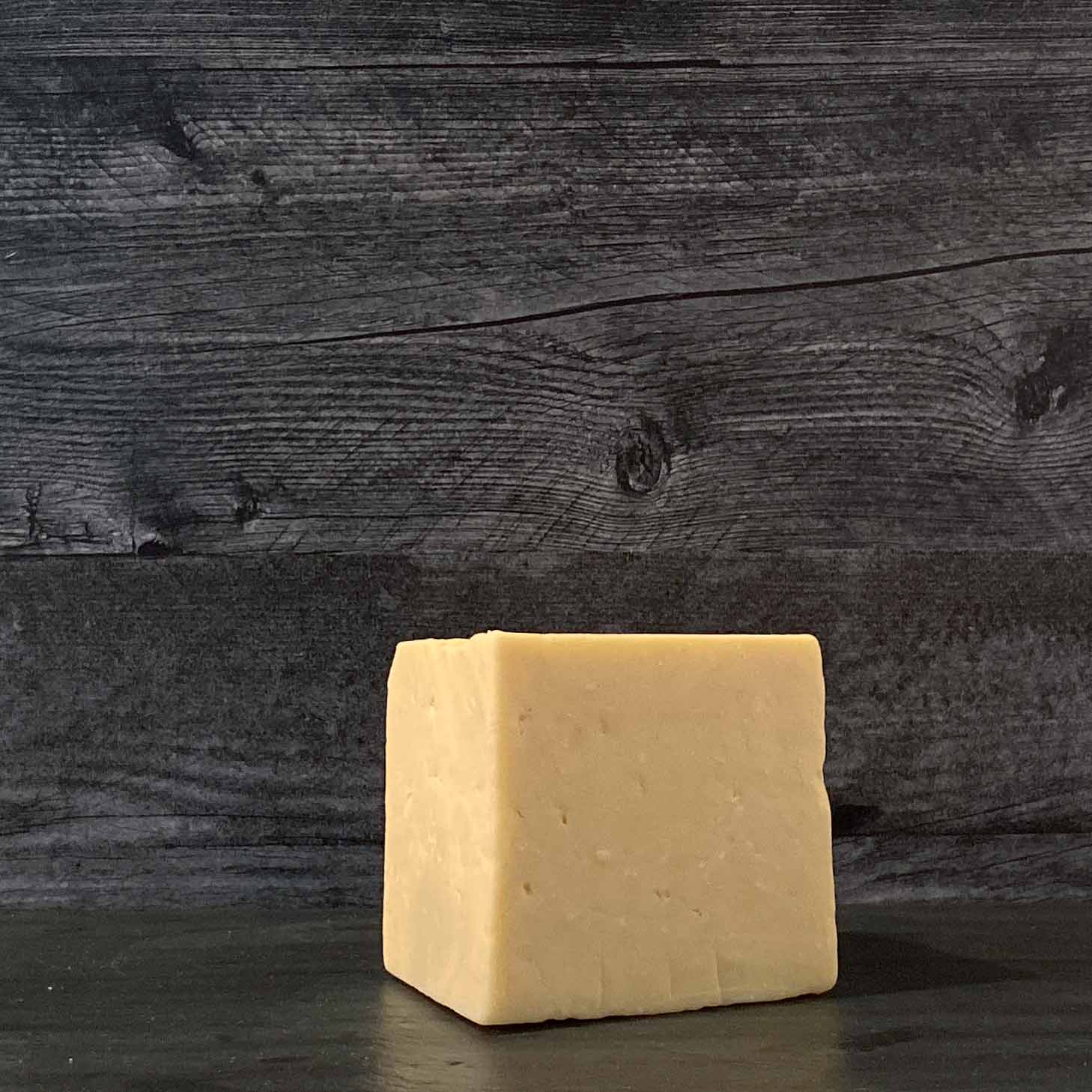 A block of Prairie Breeze Cheddar cheese on a wooden surface