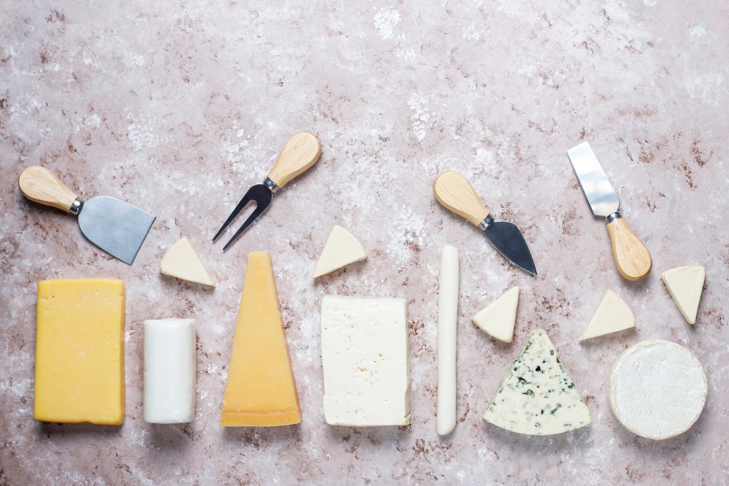 several types of cheese wedges on a light brown surface 